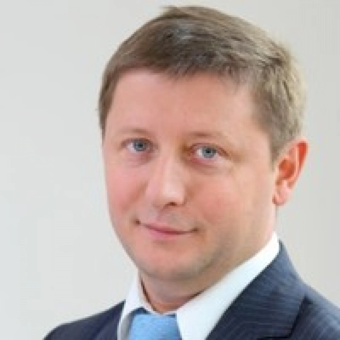 Mężczyzna w garniturze z krótkimi włosami, patrzący w stronę kamery.