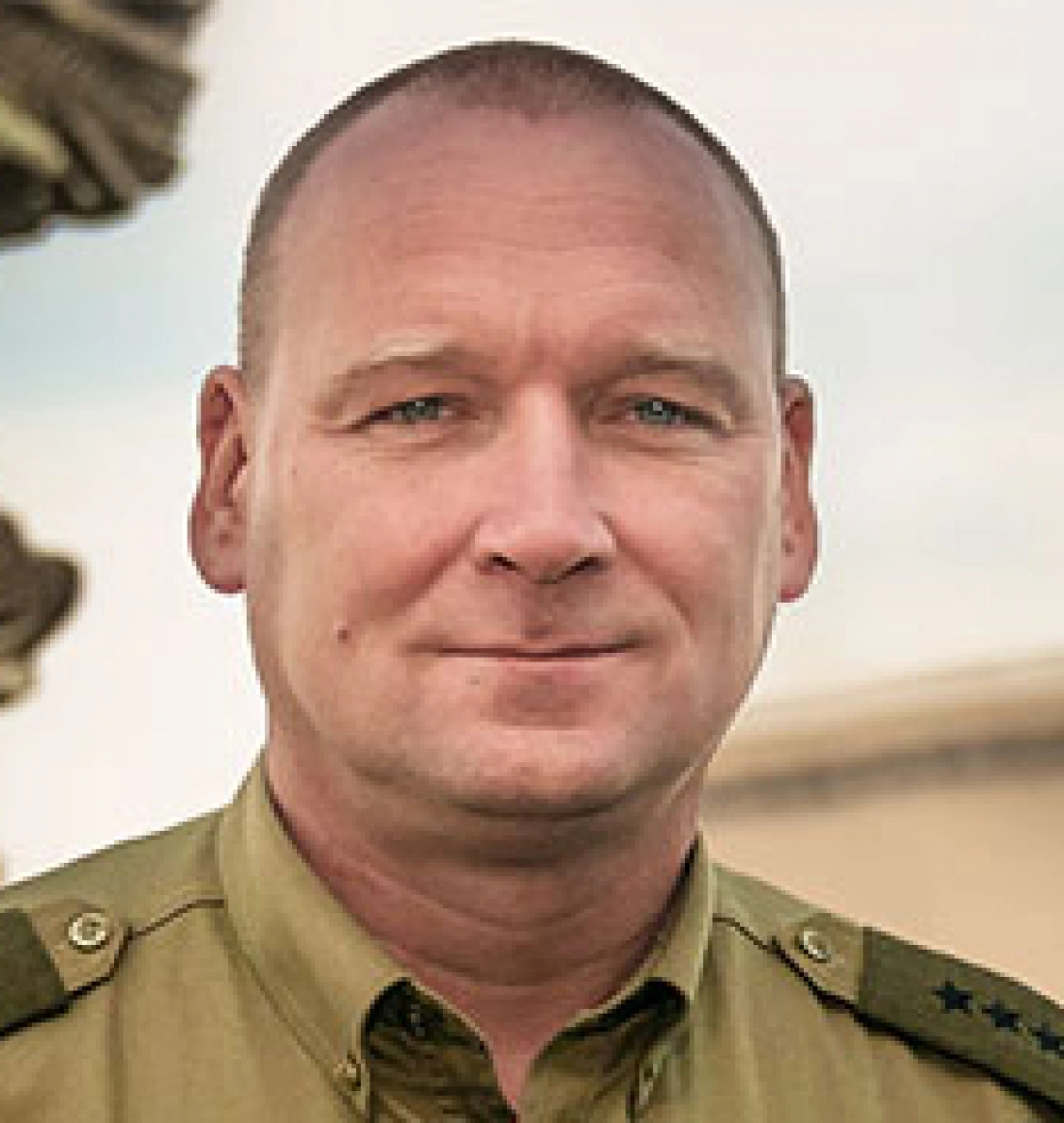 Mężczyzna w mundurze wojskowym, patrzący w kamerę.