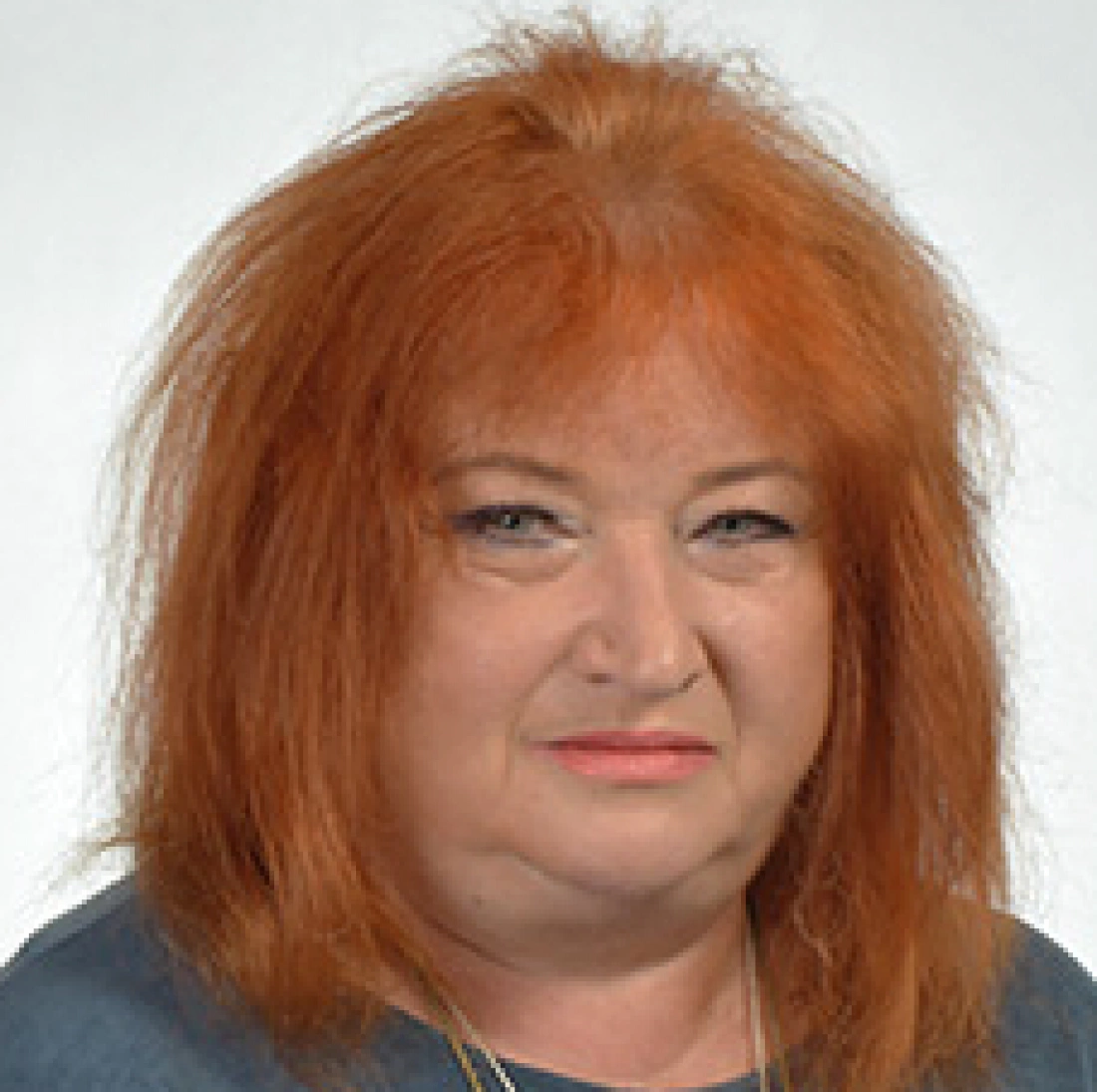 Portret osoby z rudymi włosami o lekko nieuporządkowanej fryzurze, patrzącej wprost.