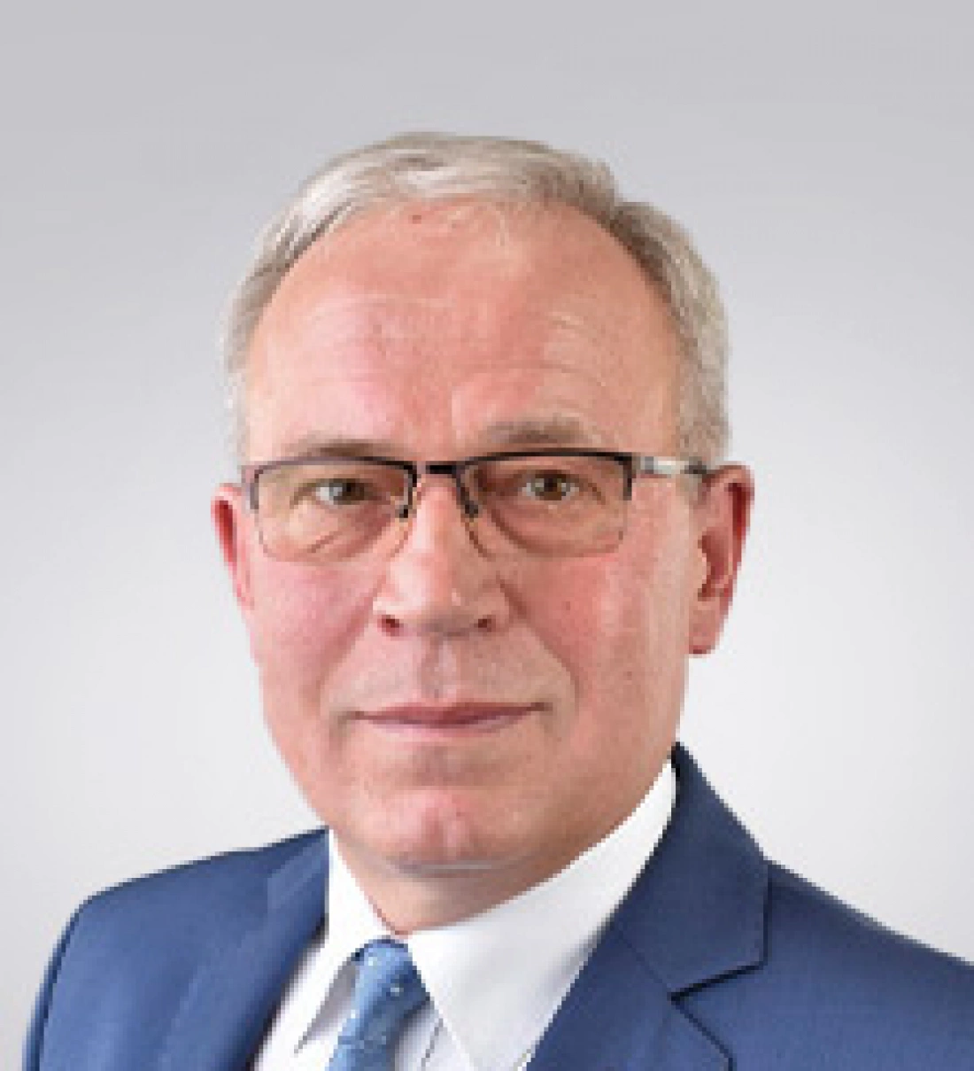 Mężczyzna w okularach, noszący niebieski garnitur i krawat.