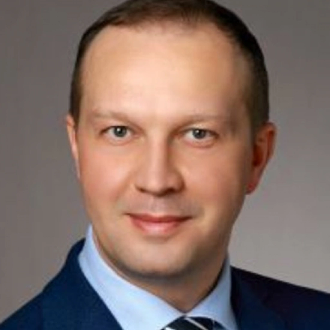 Mężczyzna w garniturze, uśmiechający się do aparatu.