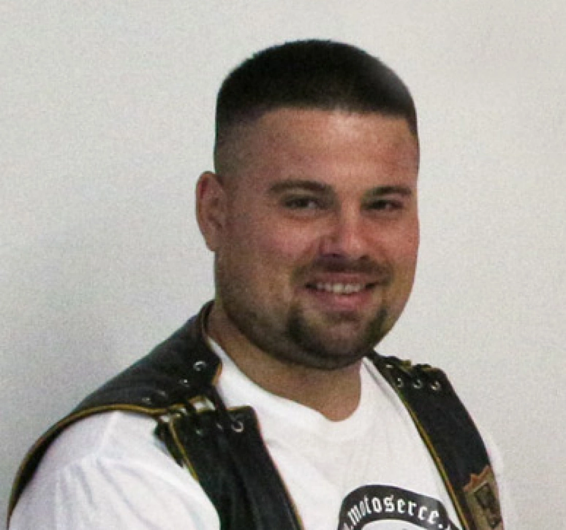 Mężczyzna w kamizelce, uśmiechający się do kamery.