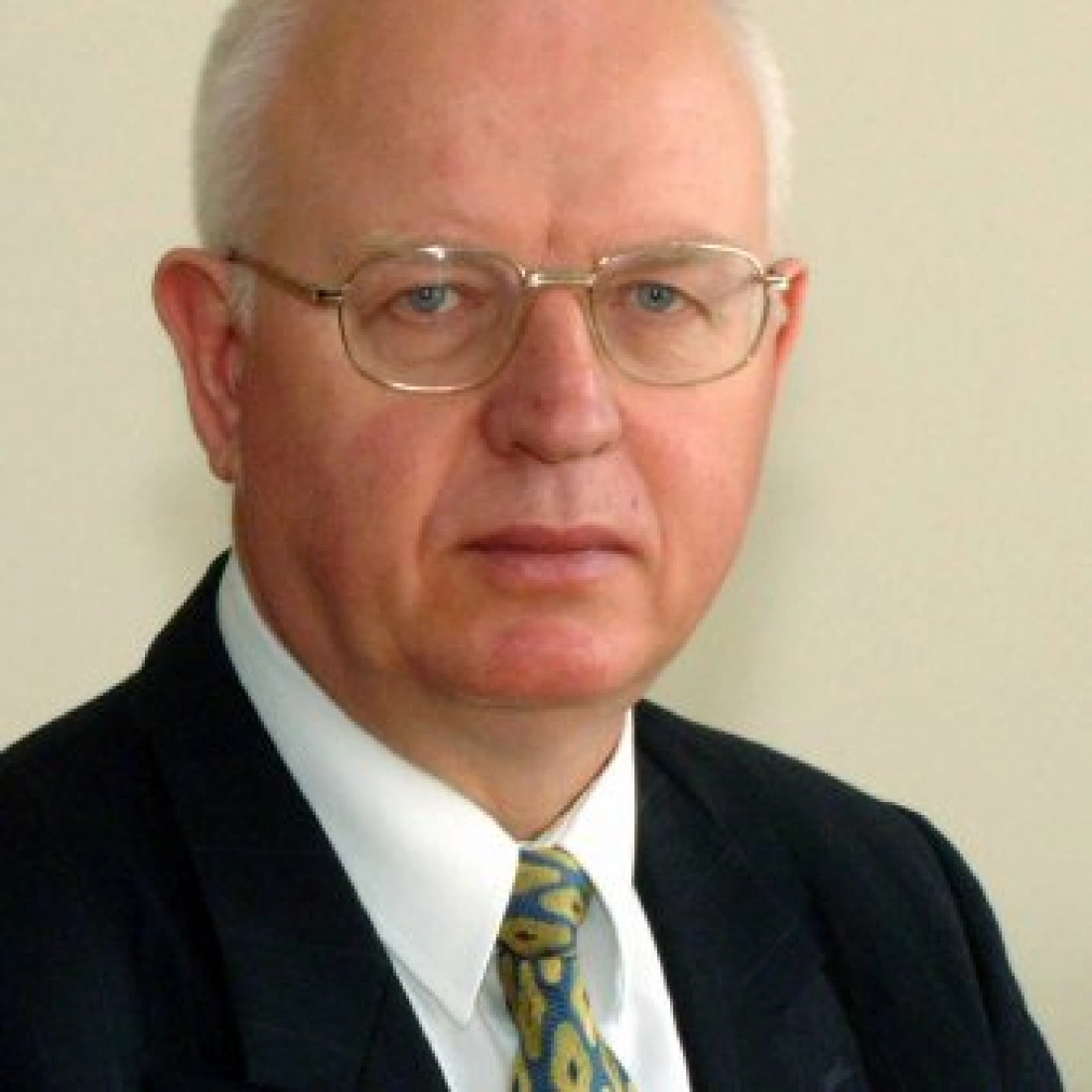 Mężczyzna w okularach, ubrany w garnitur i krawat.