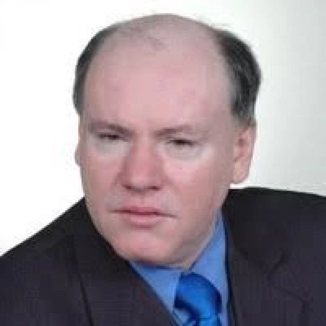 Mężczyzna w eleganckim ubraniu, z poważnym wyrazem twarzy.