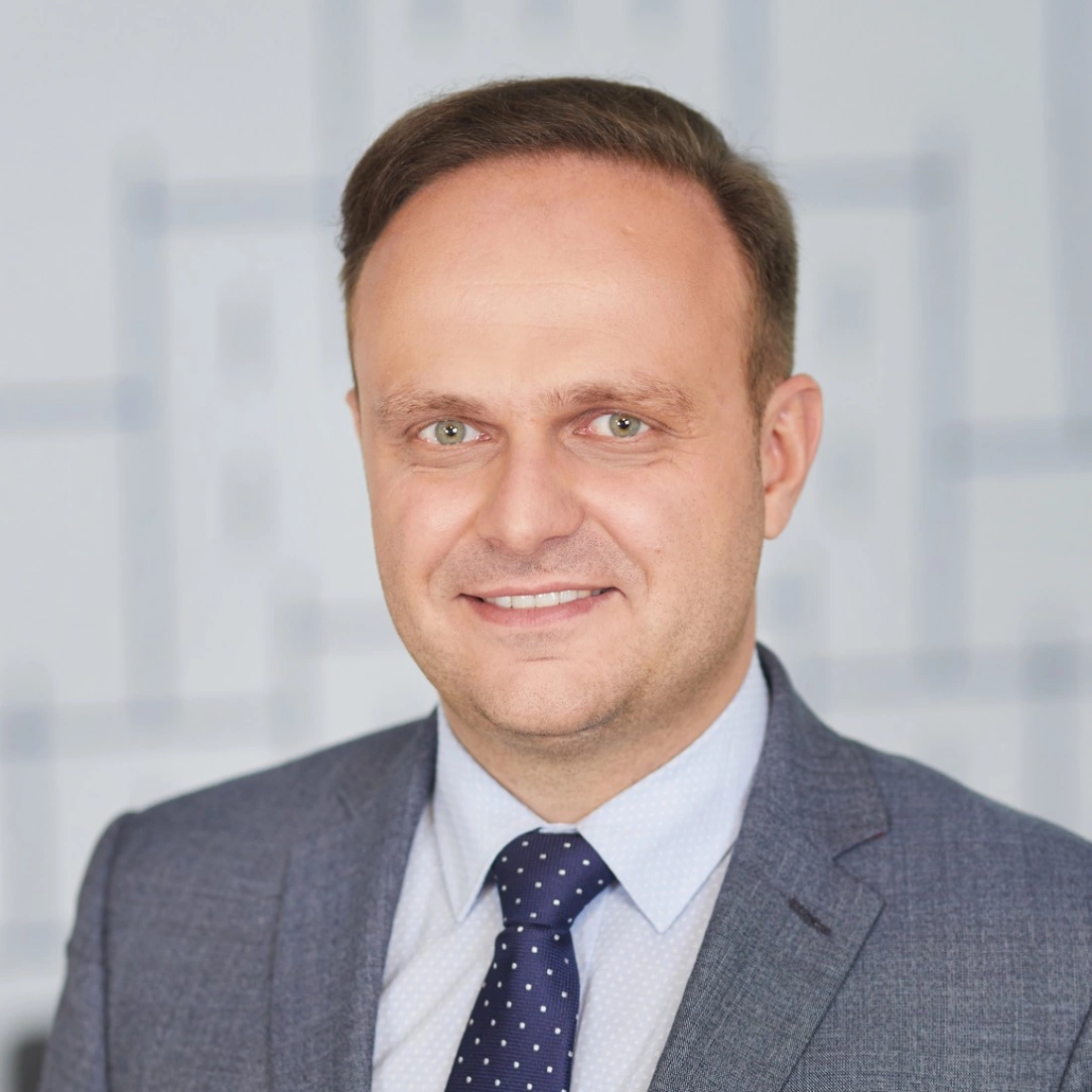 Mężczyzna w eleganckim garniturze, uśmiechający się do kamery.