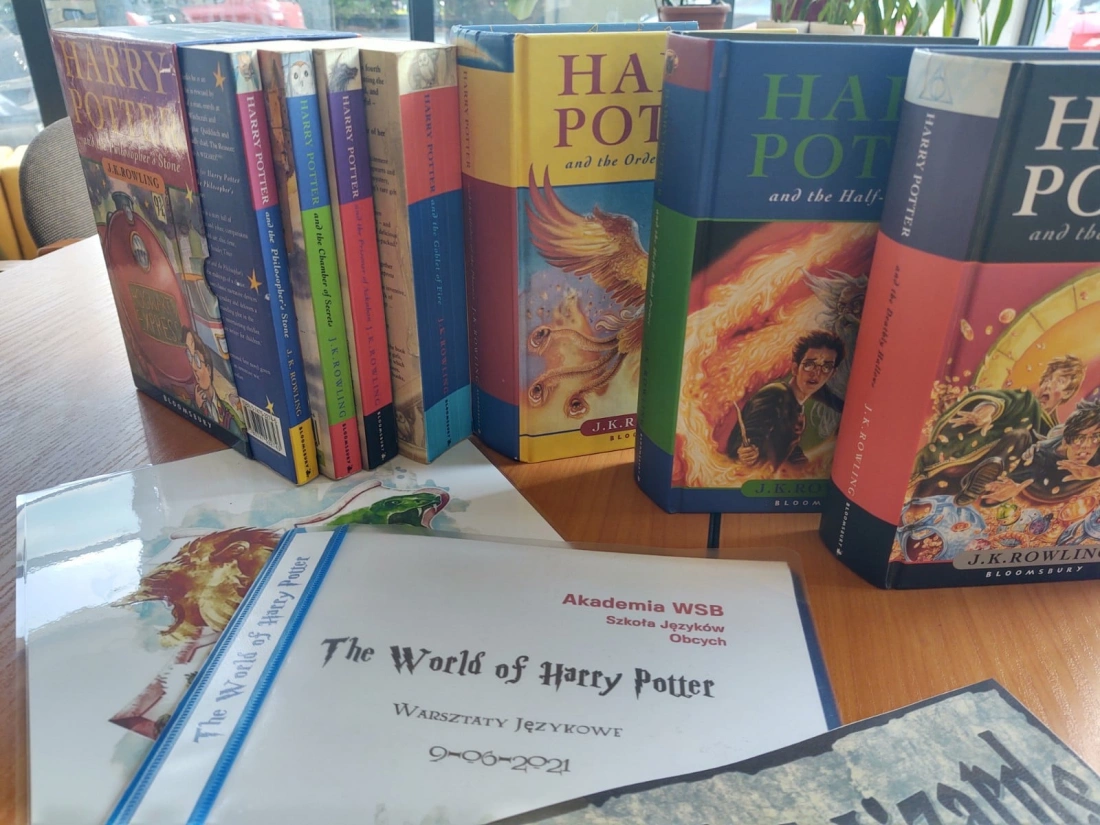 Na stole leżą książki z serii "Harry Potter" oraz materiały związane z warsztatami językowymi.
