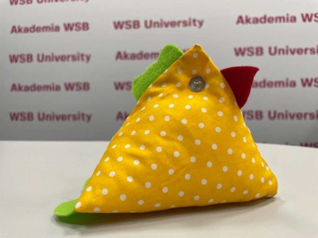 Kolorowa, żółta poduszka w kształcie kurczaka z groszkowym wzorem.