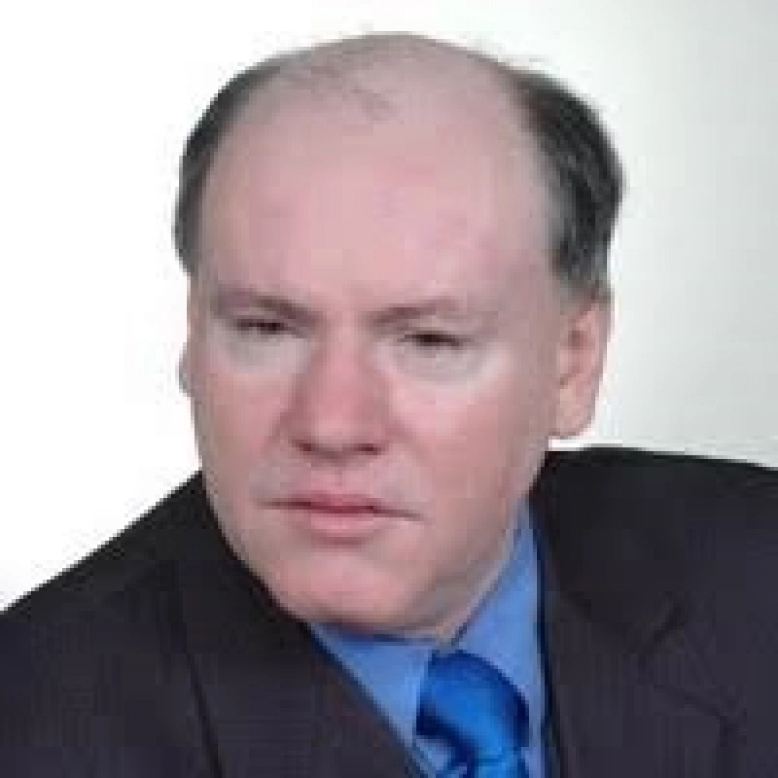 Mężczyzna w garniturze z nieco poważnym wyrazem twarzy.