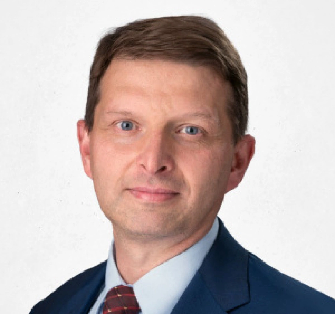 Mężczyzna w eleganckim garniturze z uśmiechem na twarzy.