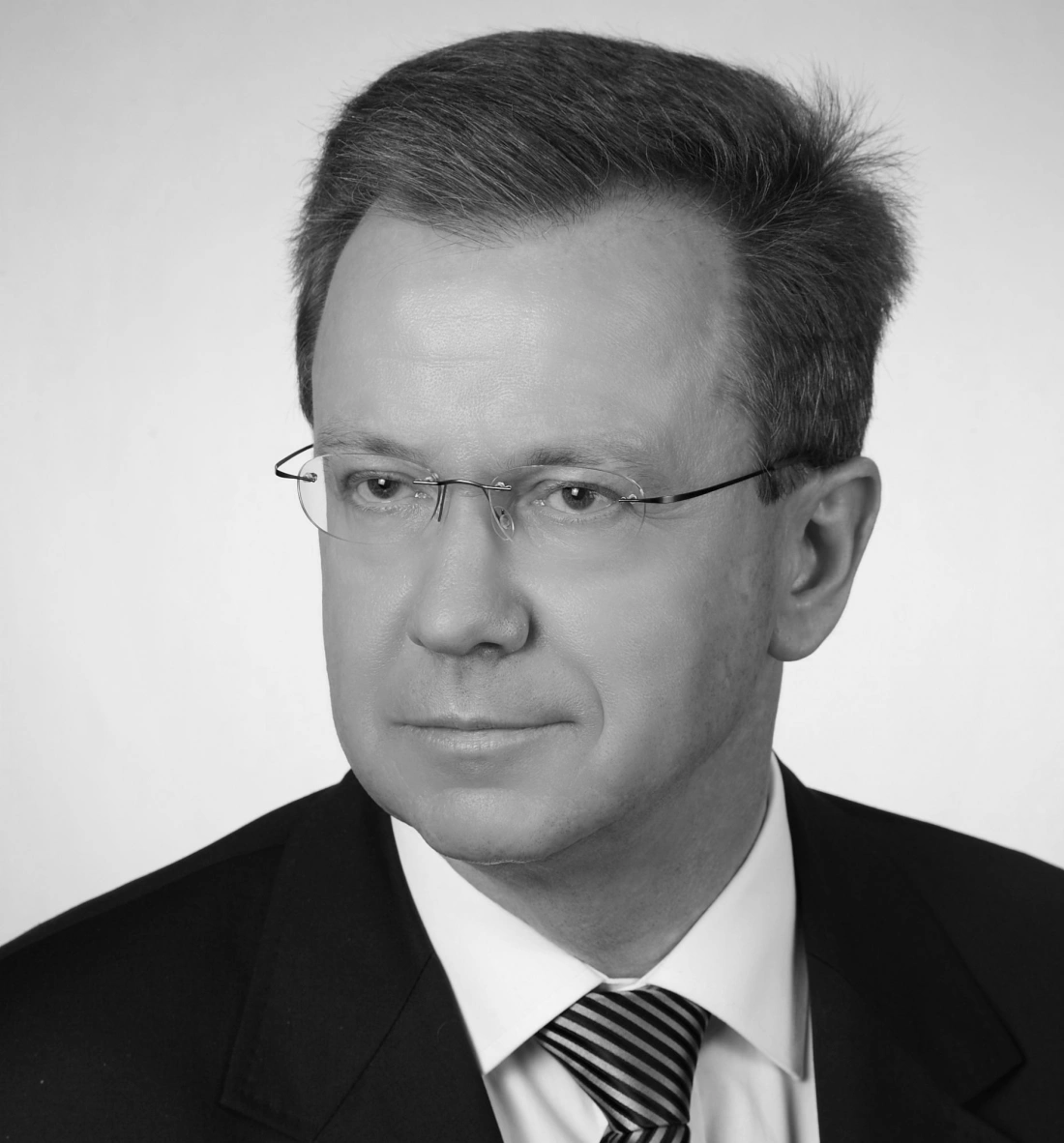 Czarno-białe zdjęcie mężczyzny w garniturze z okularami.