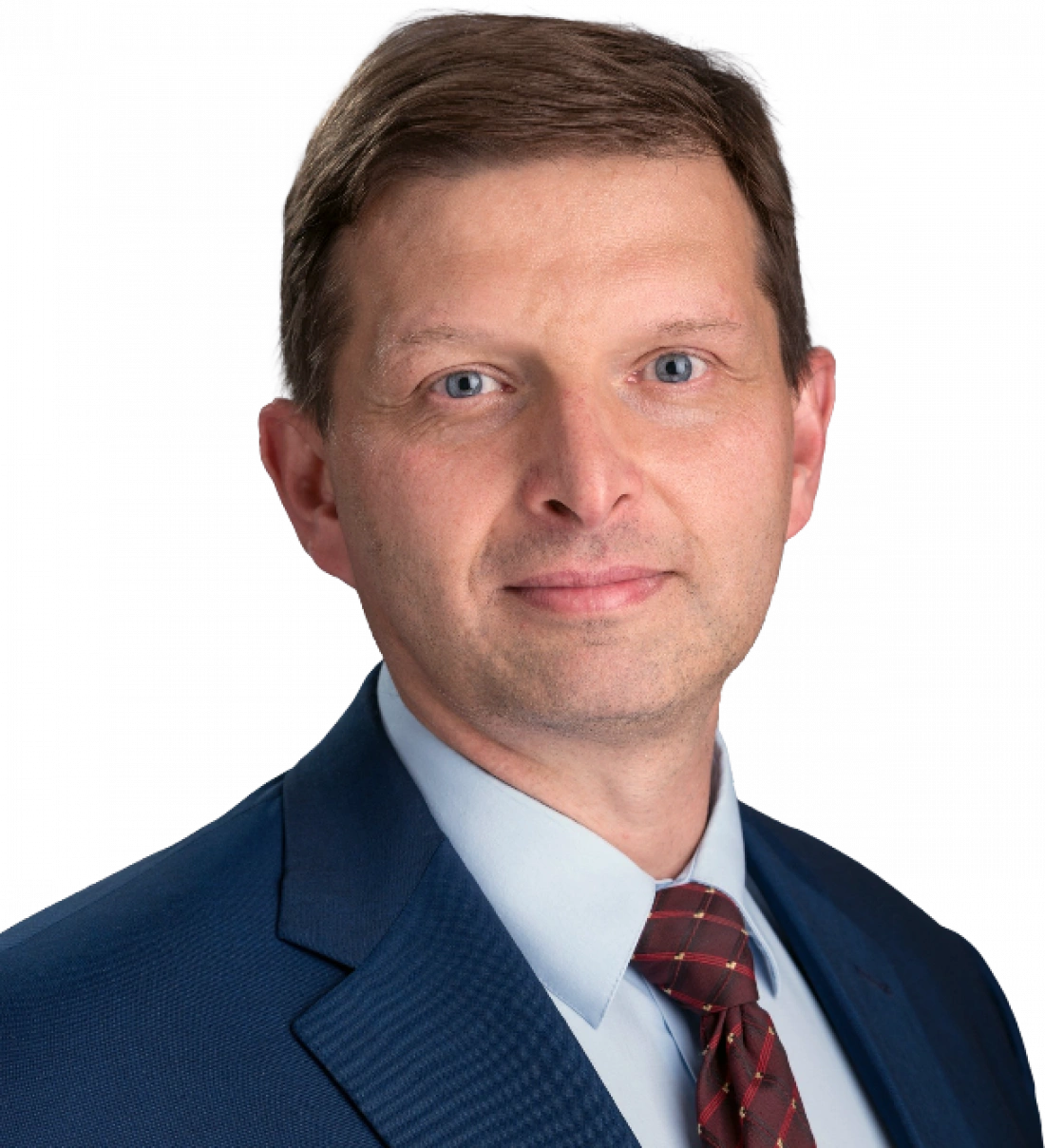 Mężczyzna w garniturze, z kr&oacute;tkimi włosami, patrzy prosto w kamerę.