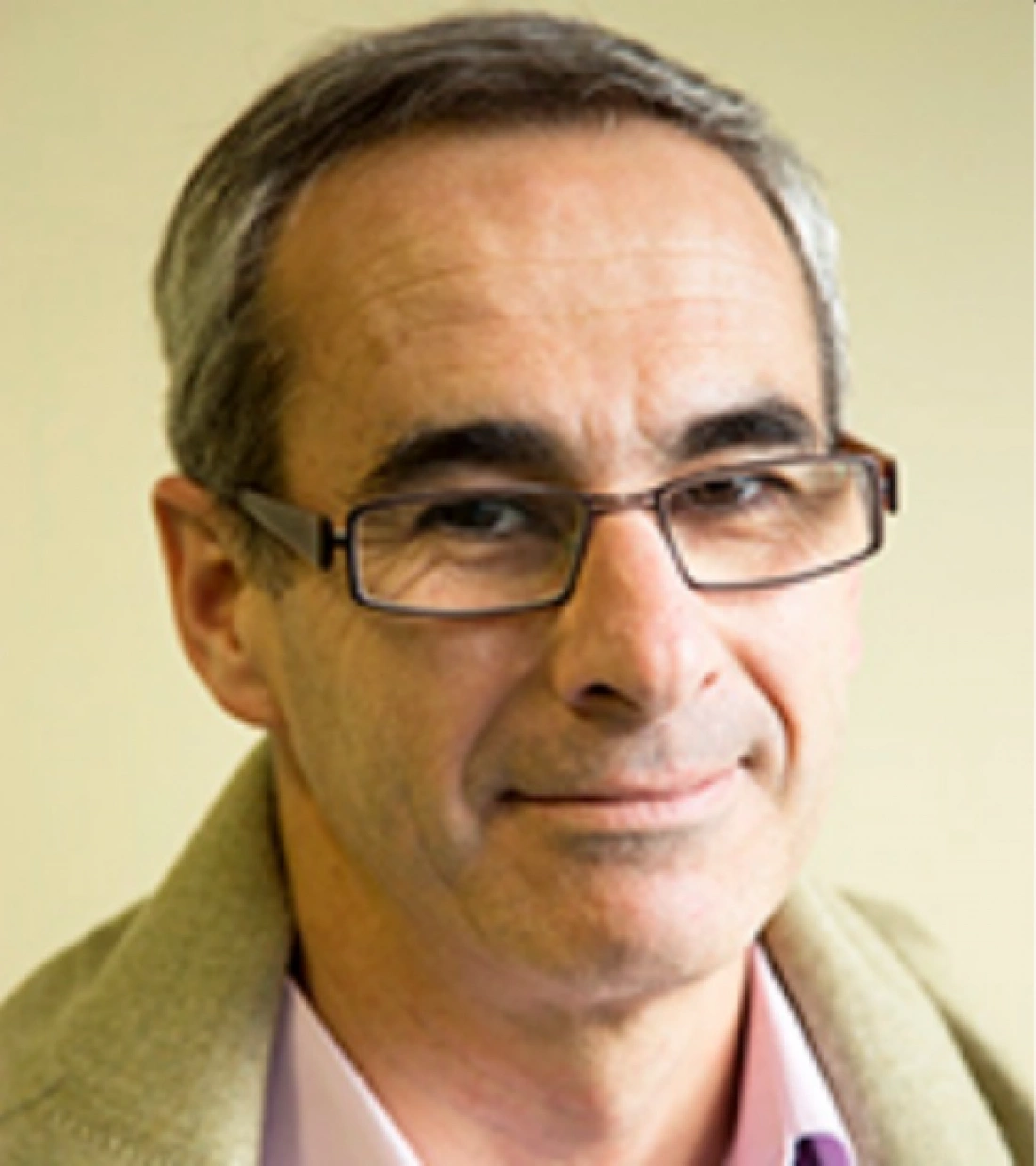 Mężczyzna z okularami, uśmiechający się, w casualowym stroju.