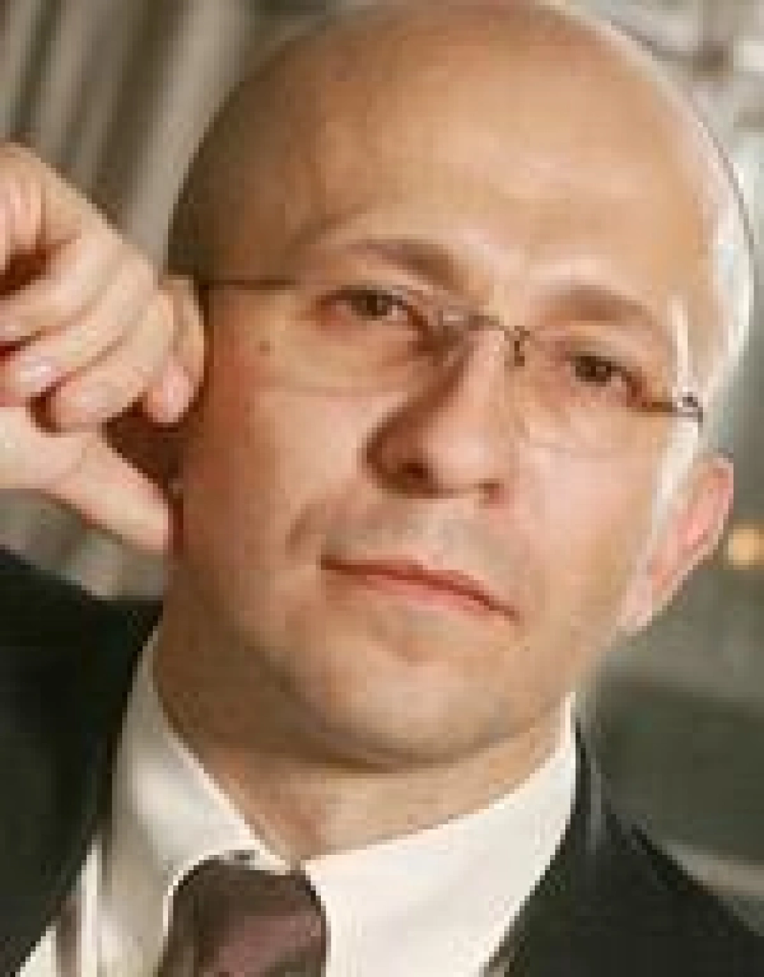 Mężczyzna w okularach, z wyrazem twarzy skupionym na rozmowie.