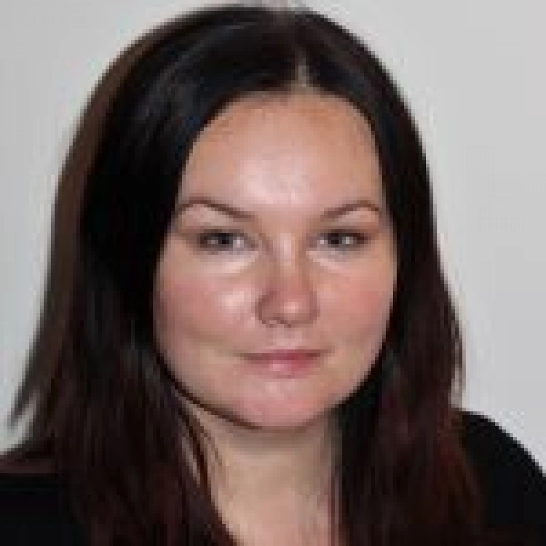 Portret młodej kobiety z ciemnymi włosami i naturalnym makijażem.