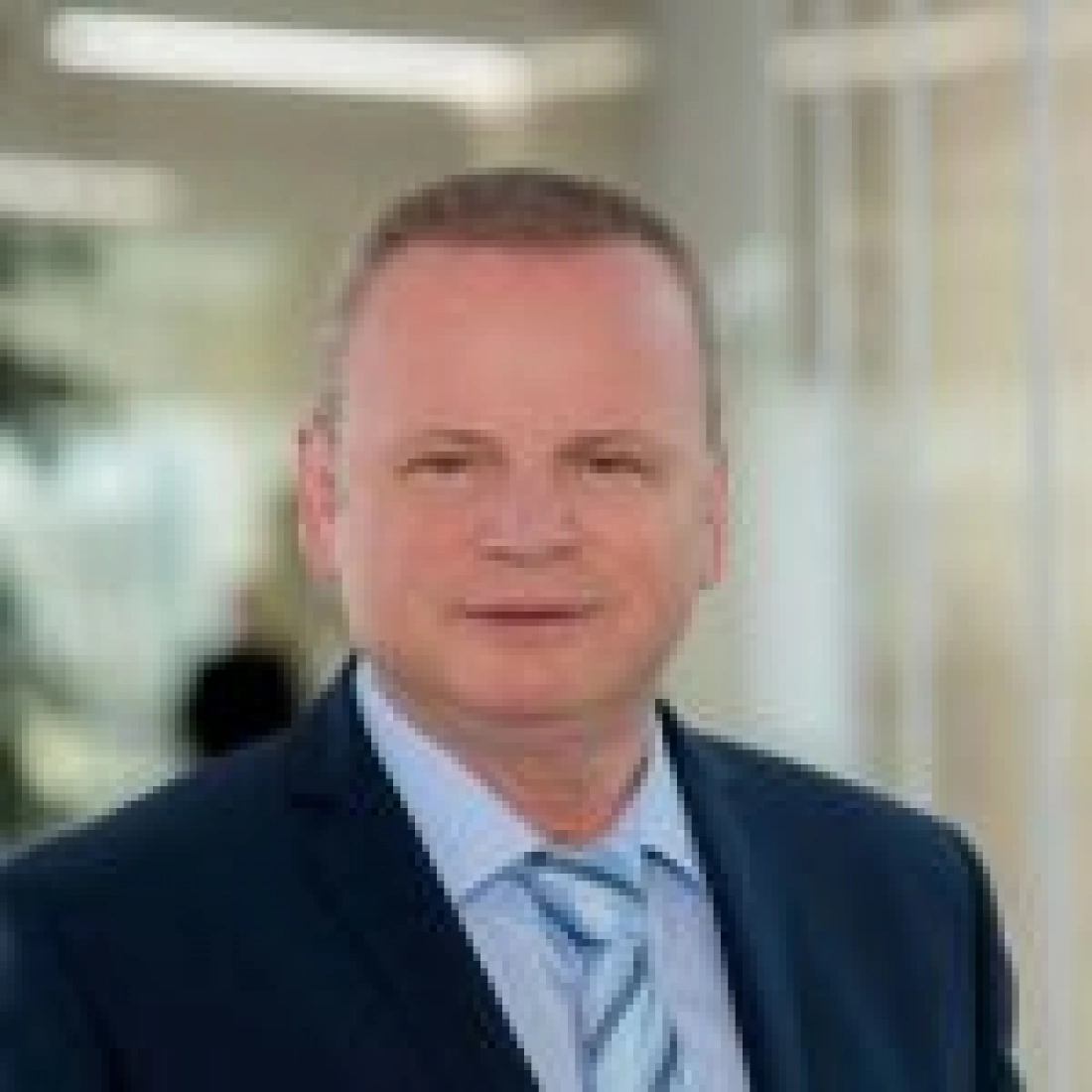 Mężczyzna w garniturze z krawatem, stojący w biurze.