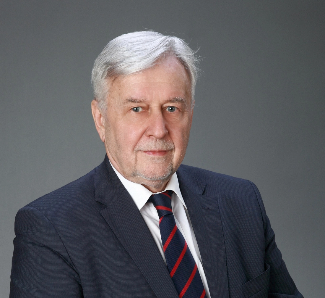 Mężczyzna w średnim wieku, ubrany w garnitur, z siwymi włosami i poważnym wyrazem twarzy.