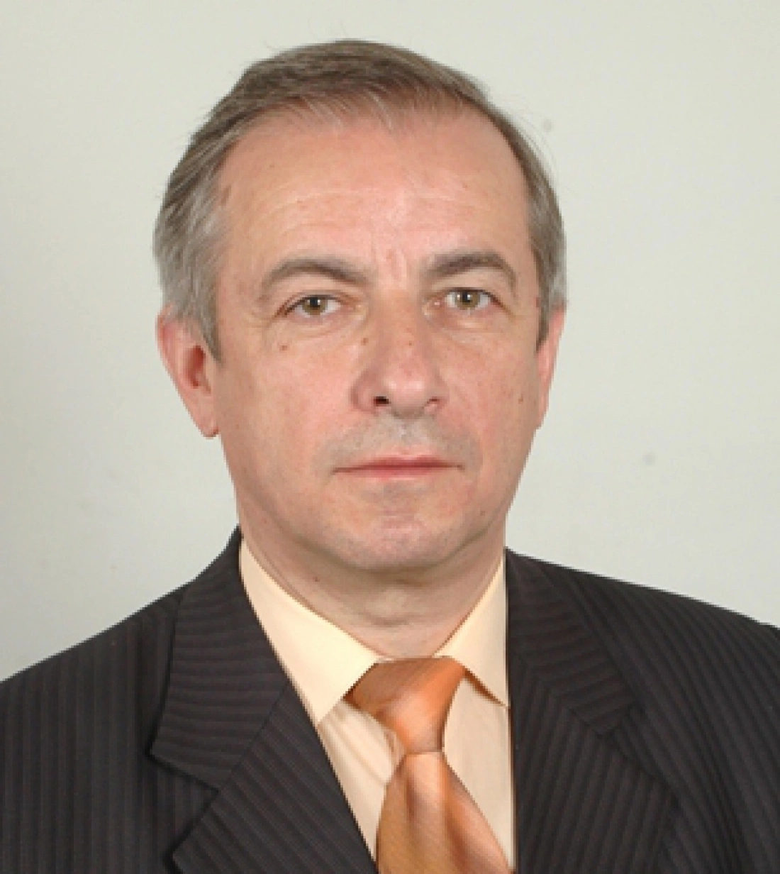 Mężczyzna w garniturze, z eleganckim krawatem, patrzy w obiektyw.