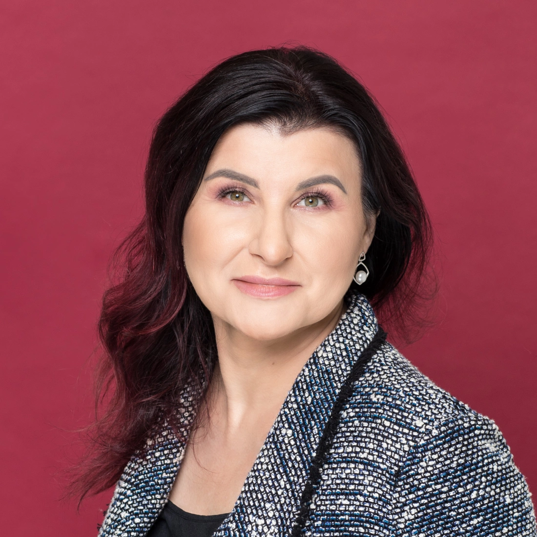 Portret kobiety w eleganckim żakiecie na tle w kolorze czerwonym.