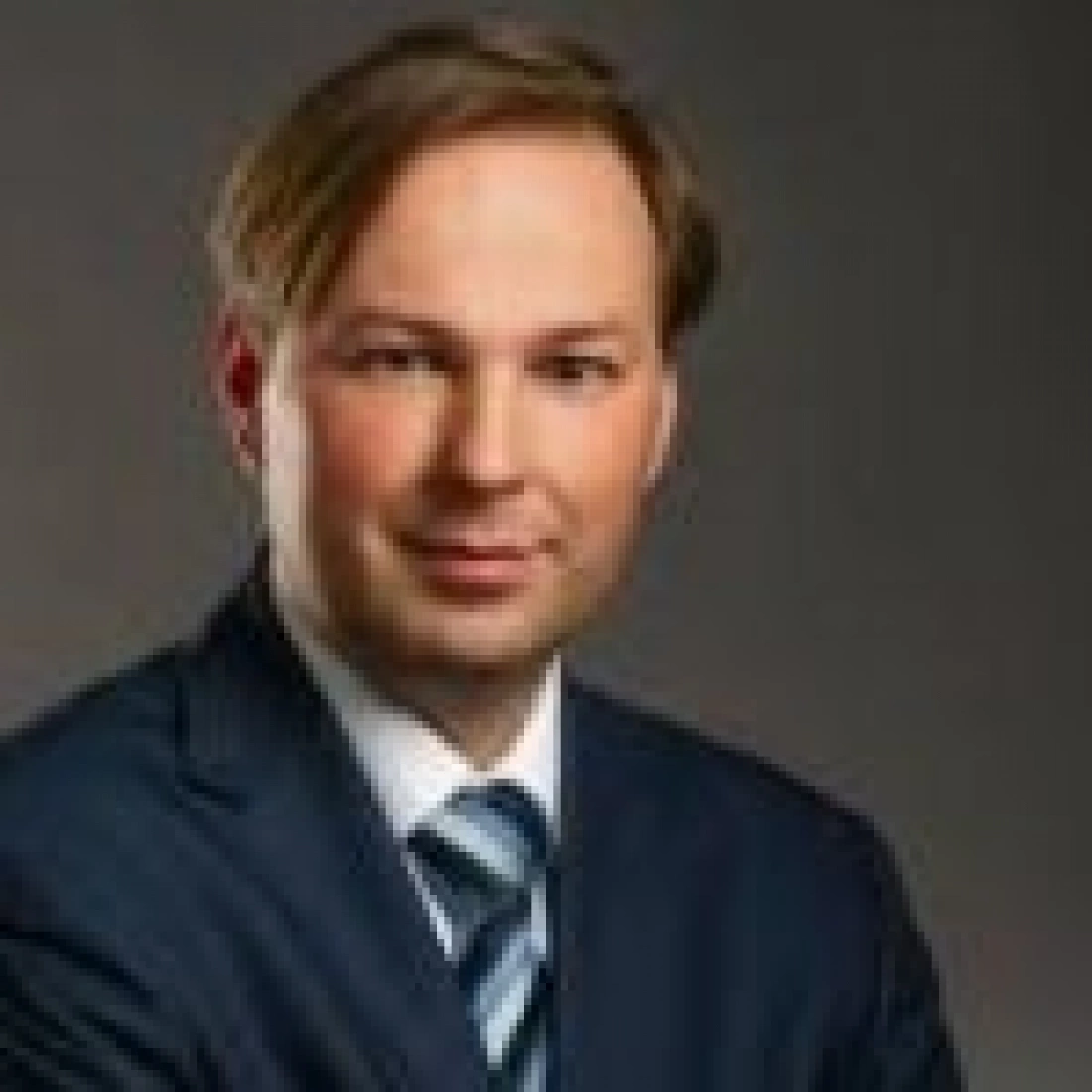 Mężczyzna w garniturze z krawatem, pozujący do zdjęcia.