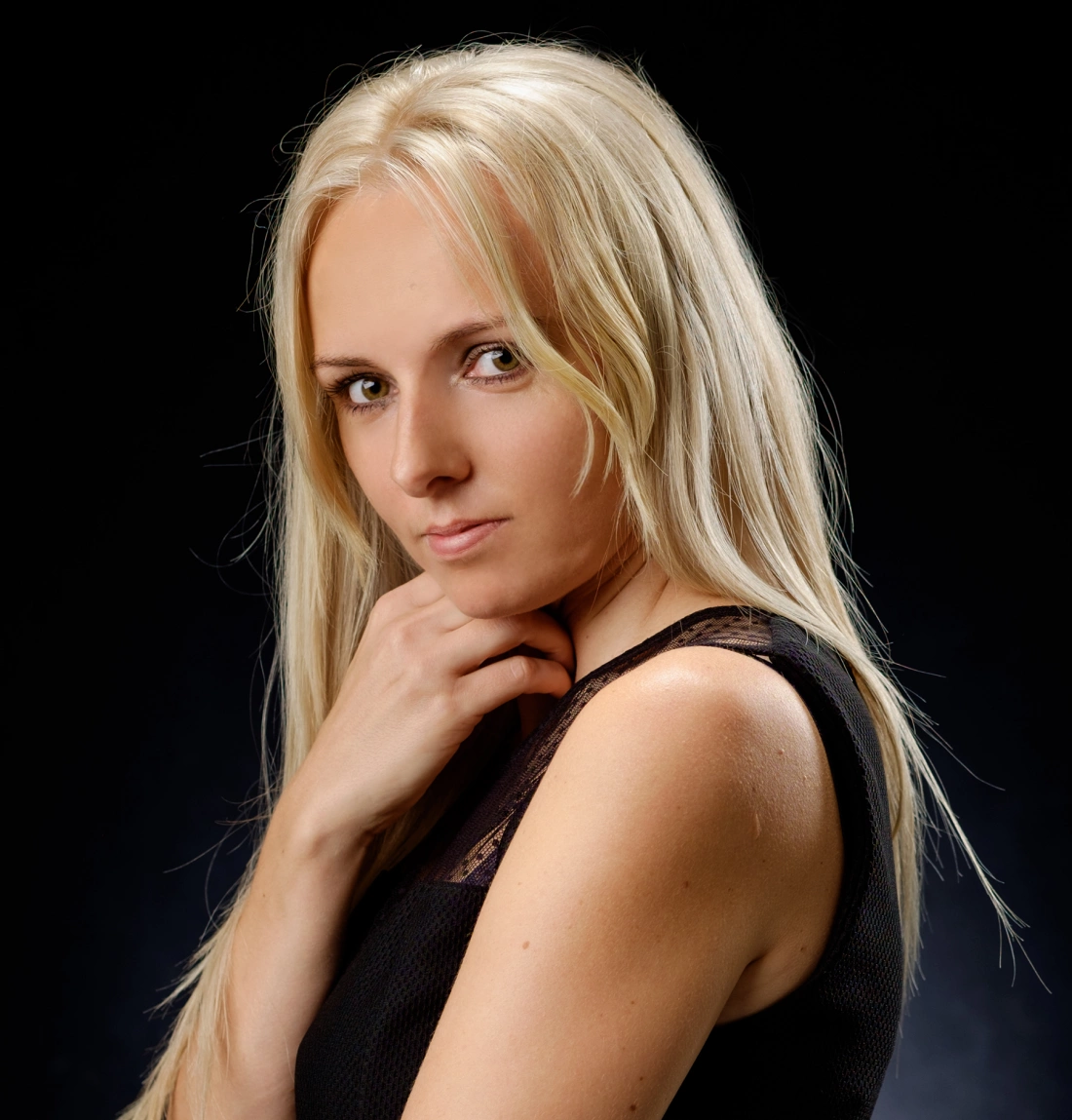 Portret kobiety z długimi blond włosami, patrzącej z pewnością w obiektyw.