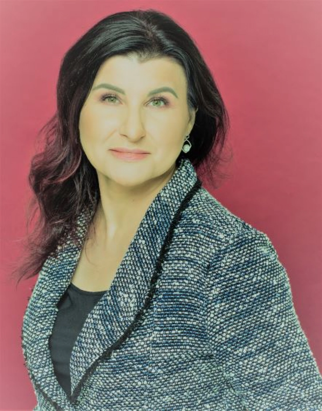 Portret kobiety w eleganckim żakiecie na tle w kolorze różowym.