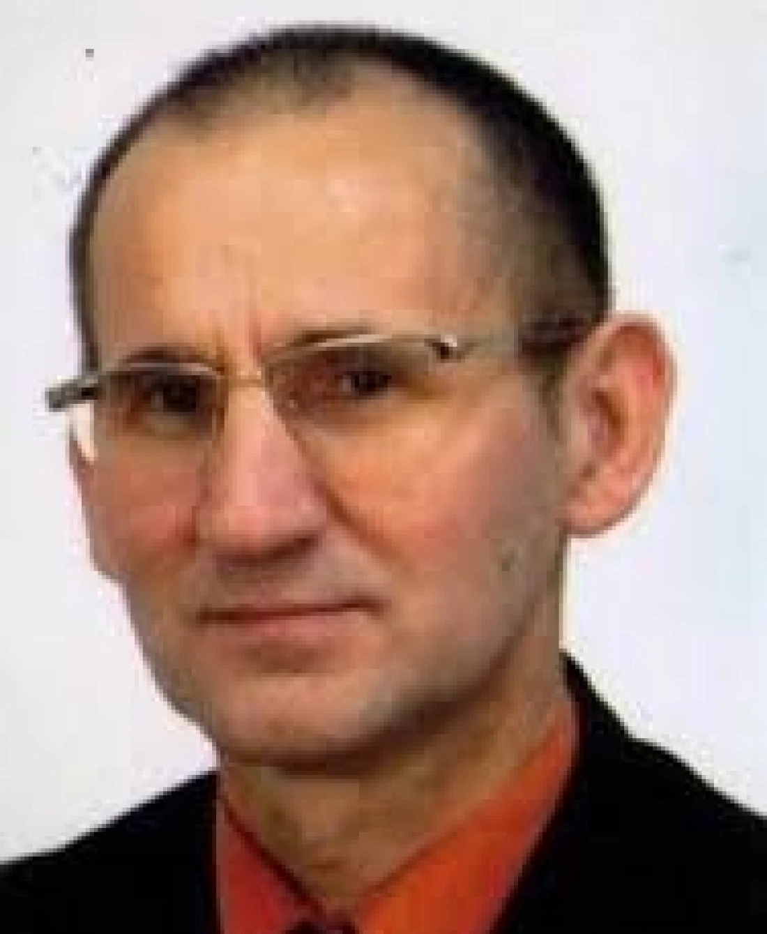 Mężczyzna w okularach, uśmiechający się, w garniturze.