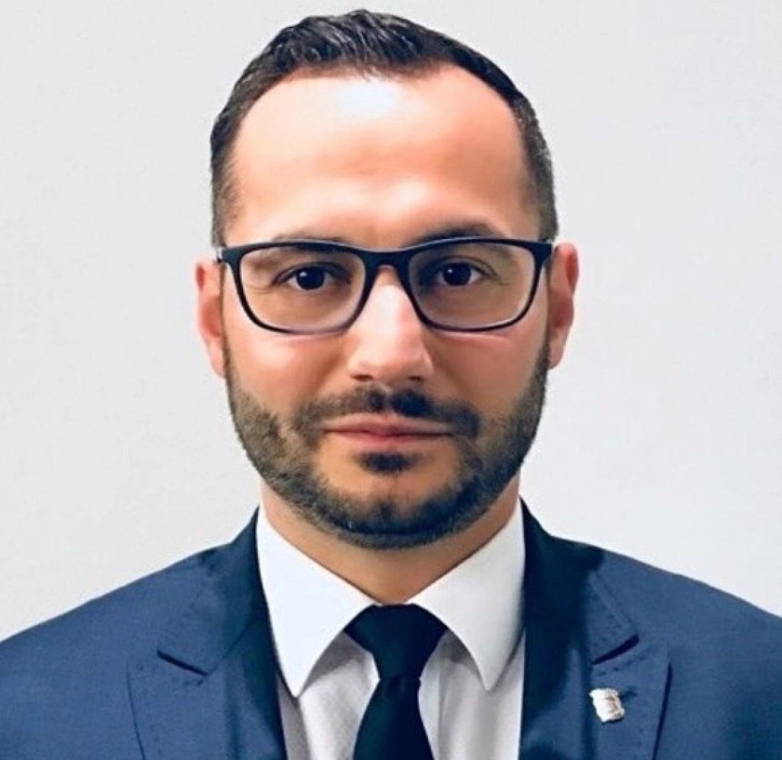 Mężczyzna w garniturze i okularach, patrzy w obiektyw.