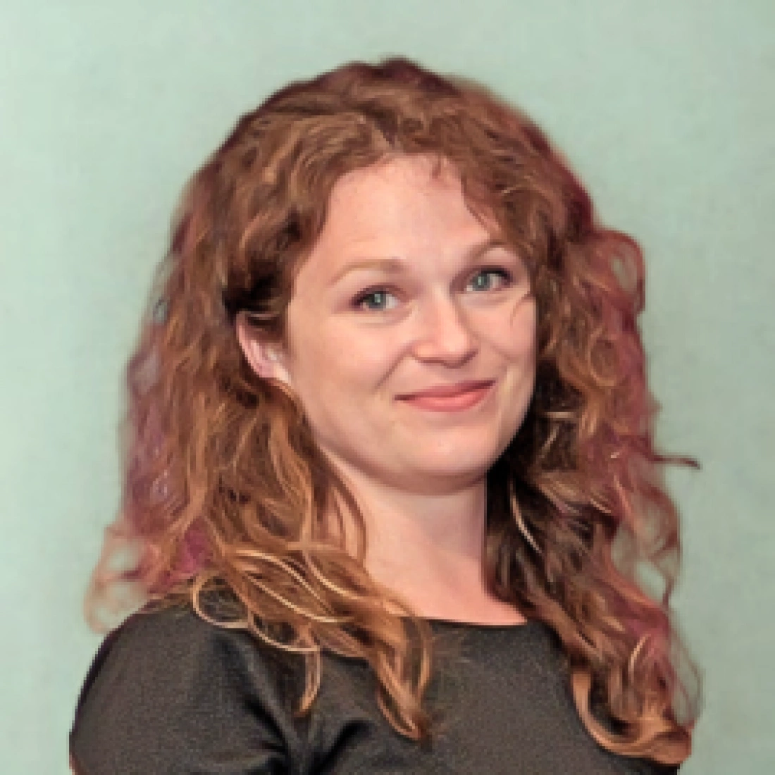 Kobieta w okularach na tle jednolitej, jasnej ściany.