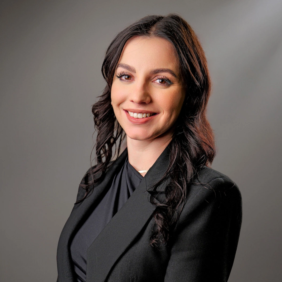 Młoda kobieta w eleganckim ubraniu, uśmiechająca się do kamery.