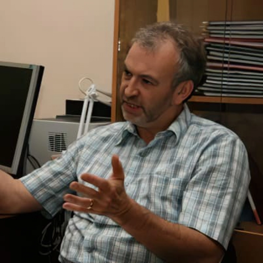 Mężczyzna w koszuli w kratkę podczas rozmowy w biurze.