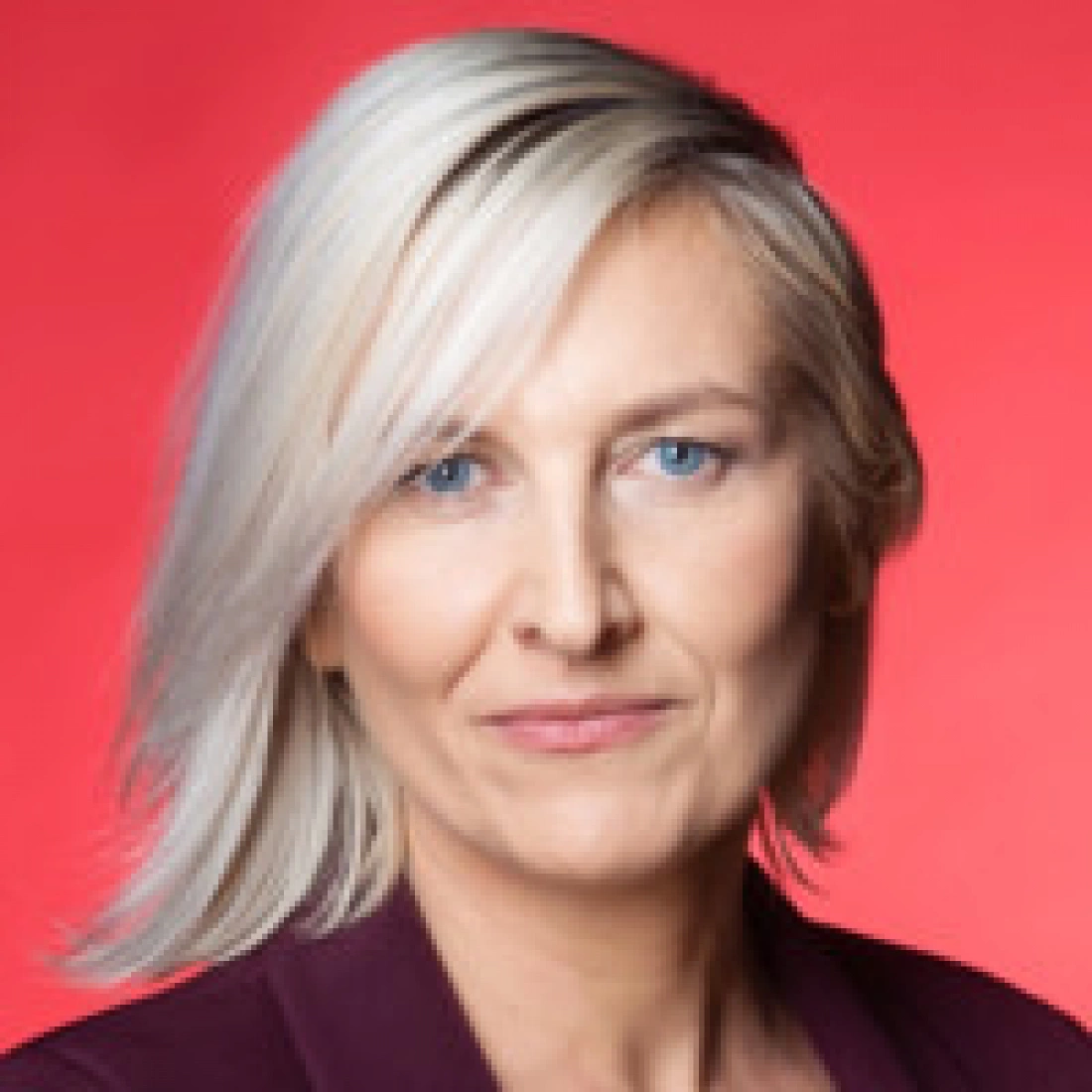 Kobieta z jasnymi włosami, wujakiem spojrzenie na tle w kolorze czerwonym.