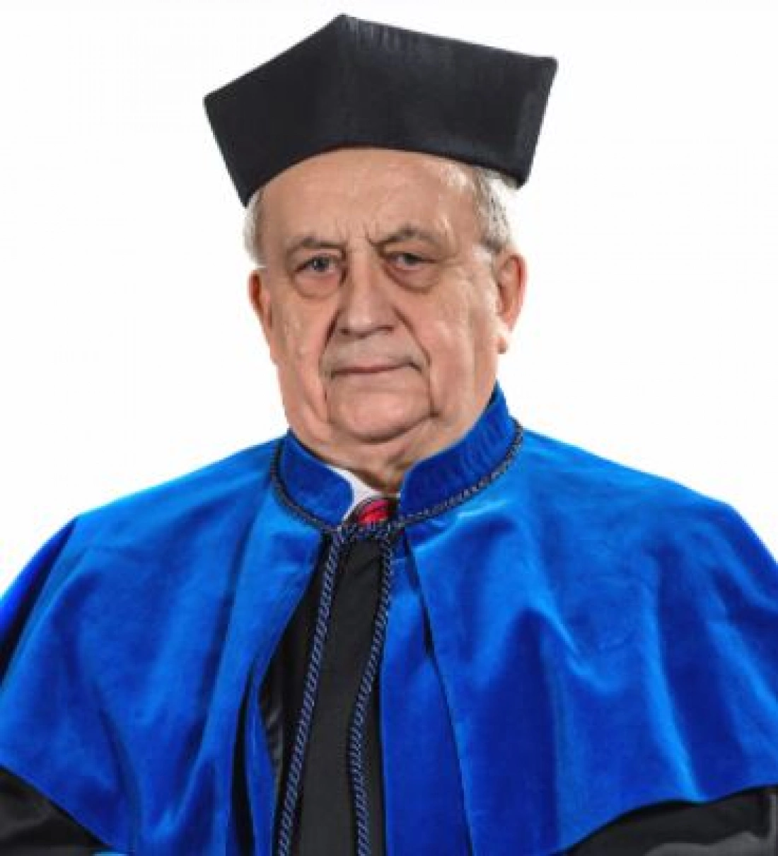 Mężczyzna w akademickim stroju z niebieską togą i czarną birettą.