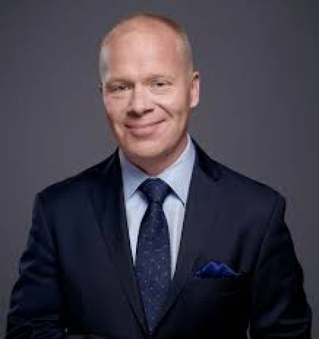 Mężczyzna w eleganckim garniturze z uśmiechem na twarzy.