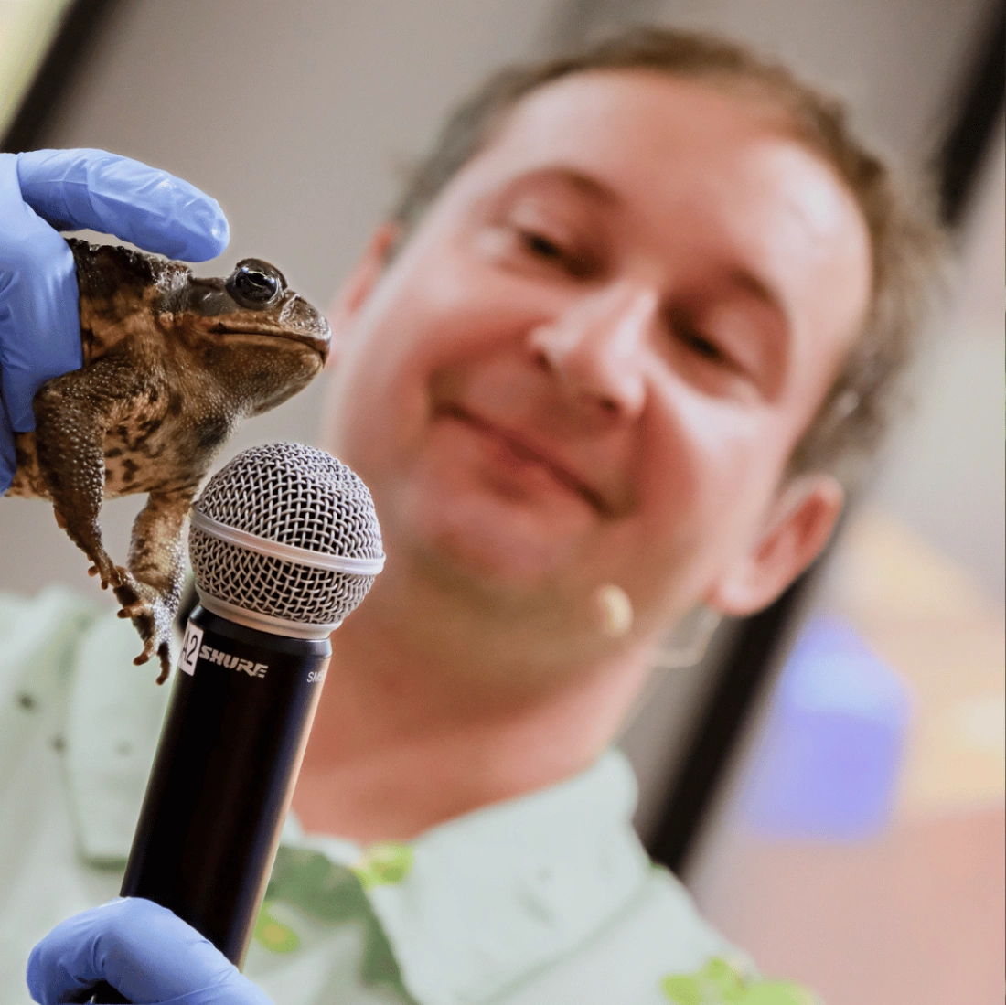 Mężczyzna w kwiecistej koszuli prezentuje materiały w sali konferencyjnej.