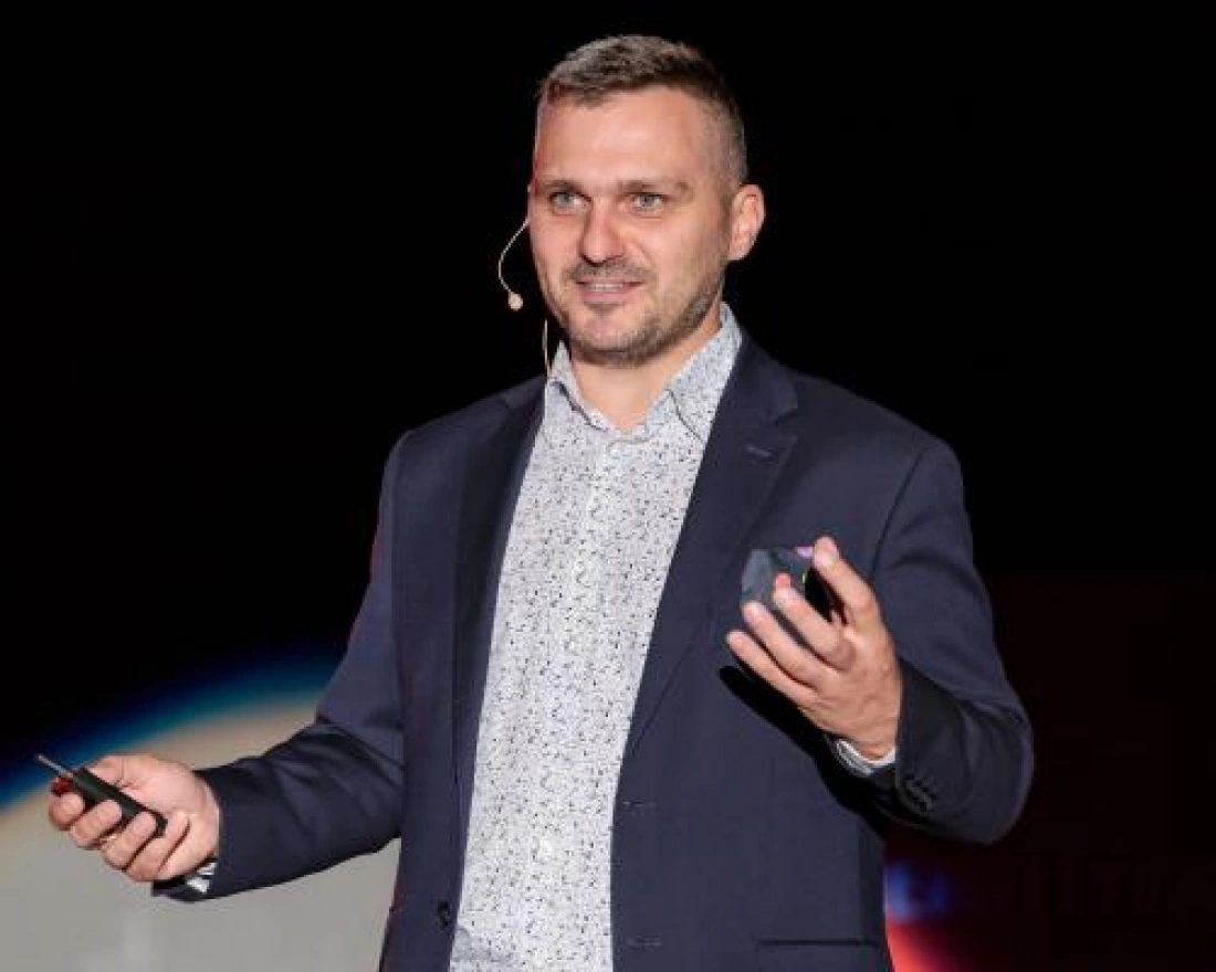 Kobieta w biurowym ubraniu z okularami na głowie, uśmiechająca się.