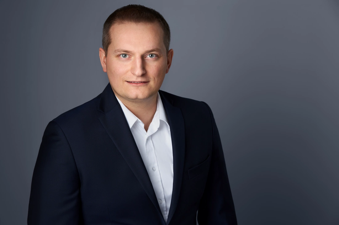 Mężczyzna w granatowym garniturze na jednolitym tle.