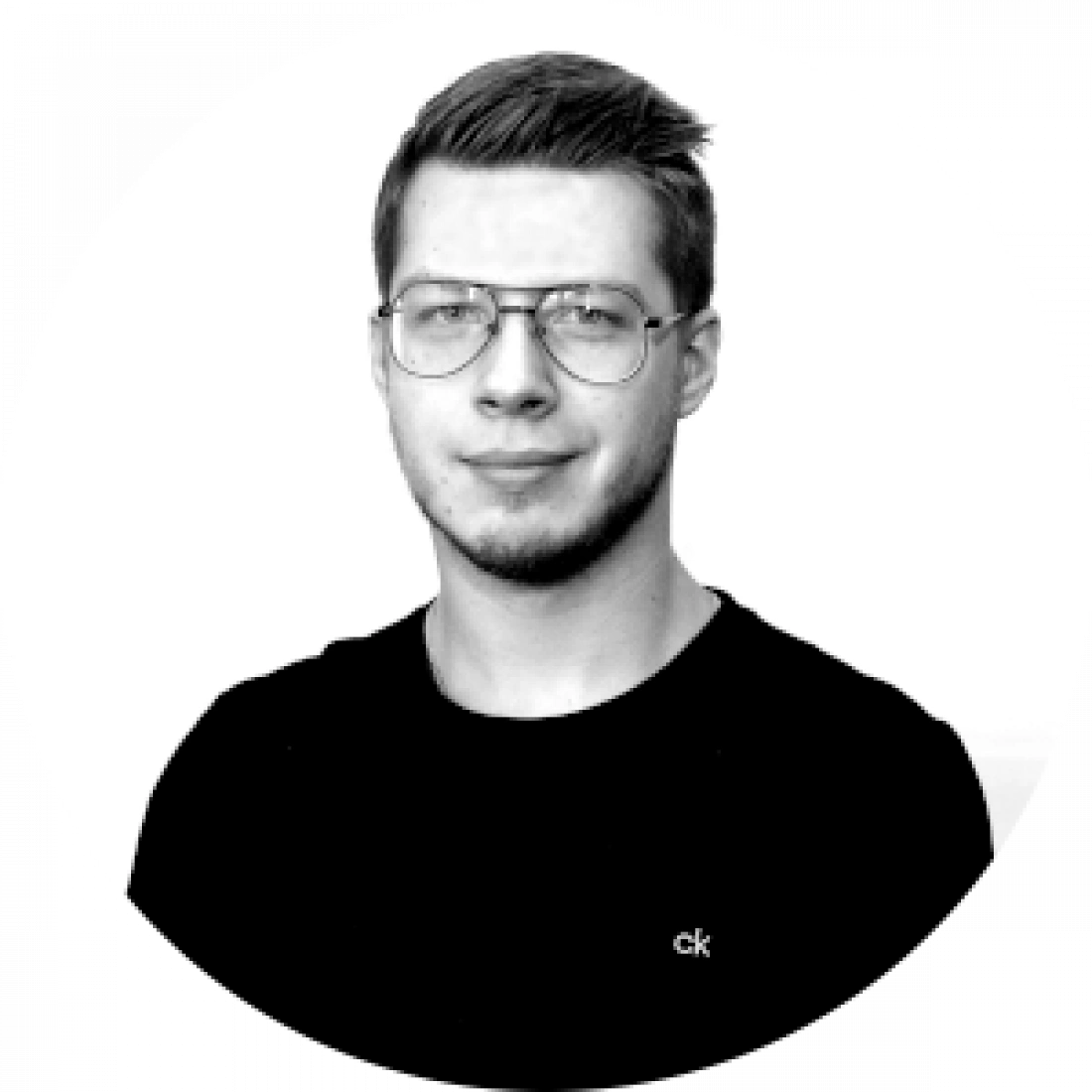 Mężczyzna w okularach, ubrany w czarną koszulkę, na tle okrągłym.