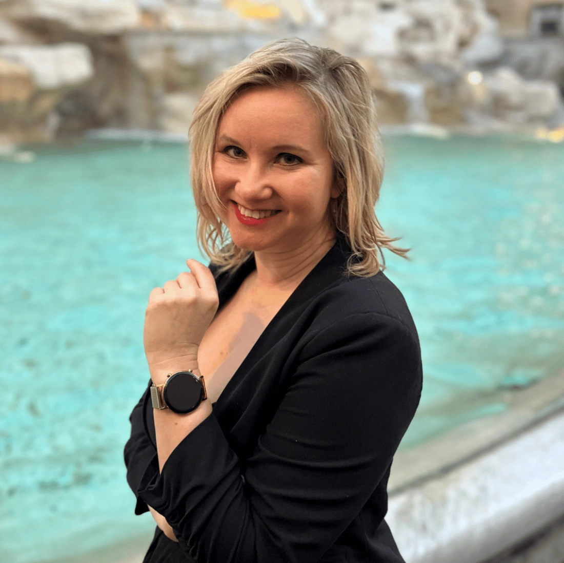 Młoda osoba z długimi, blond włosami, uśmiechająca się lekko w jasnym otoczeniu.