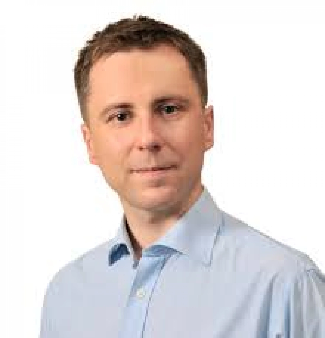 Mężczyzna w niebieskiej koszuli, patrzący w stronę obiektywu.