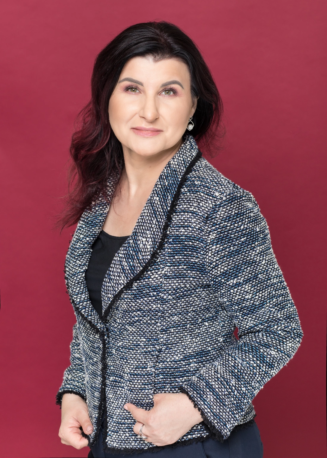 Kobieta w eleganckim żakiecie na tle w kolorze czerwonym.