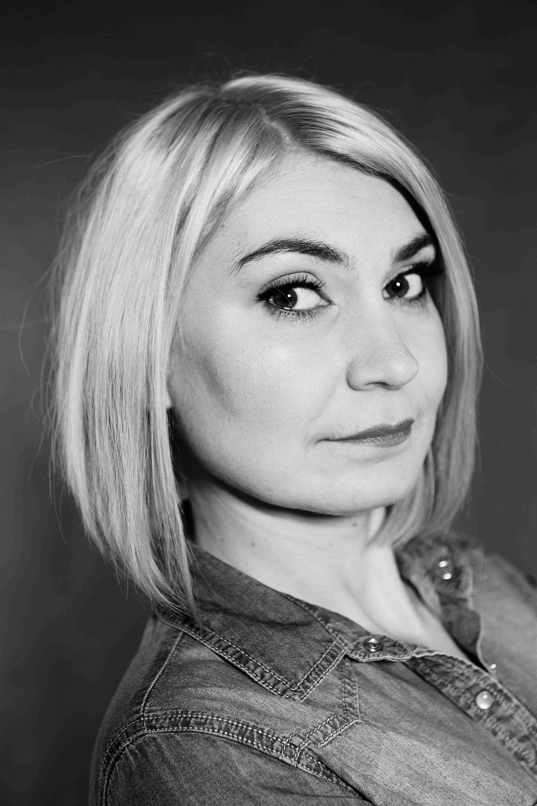 Portret kobiety z krótkimi, jasnymi włosami w czarno-białej tonacji.