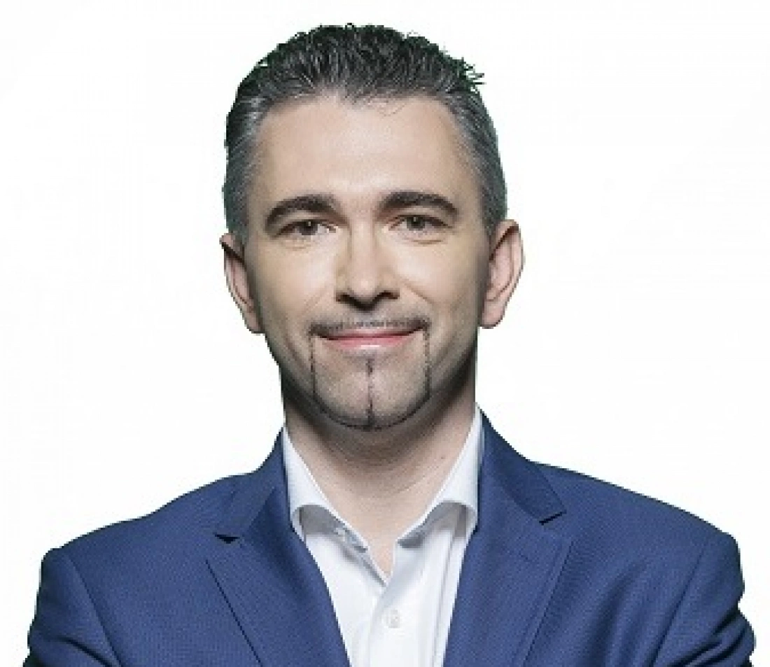 Mężczyzna w niebieskim garniturze z uśmiechem na twarzy.