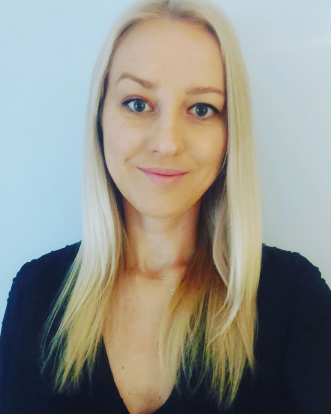 Kobieta z długimi blond włosami, uśmiechająca się.