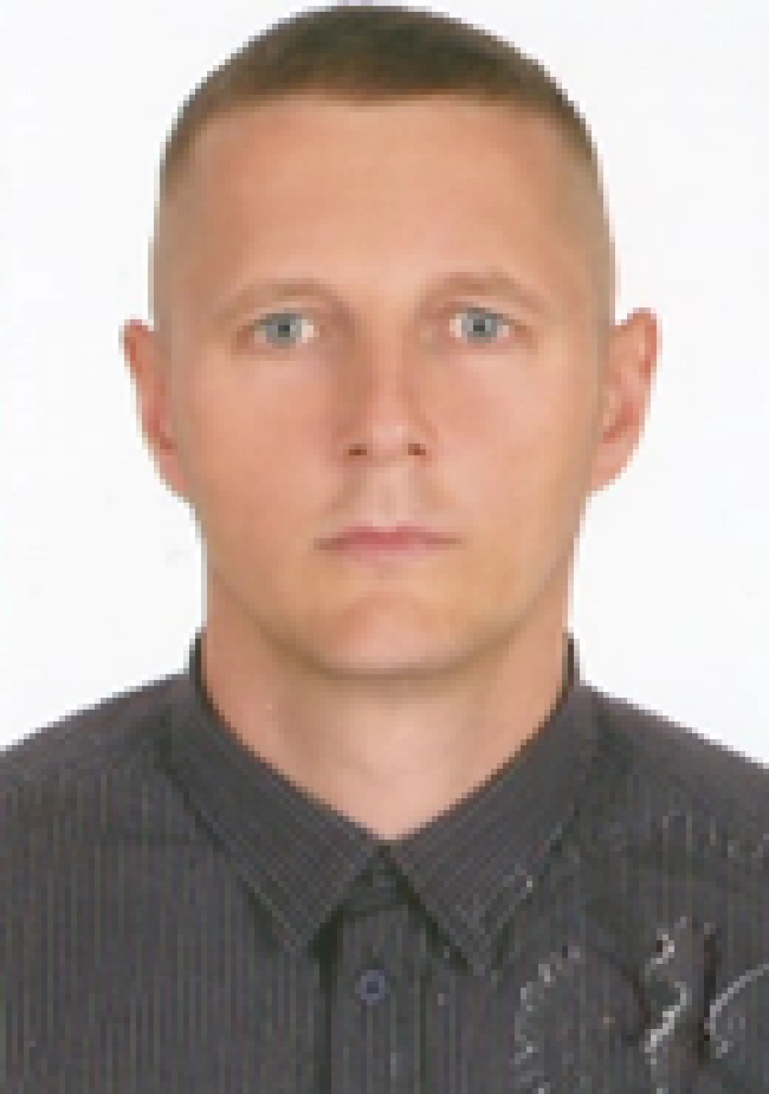 Mężczyzna w koszuli z kołnierzykiem, patrzący w stronę obiektywu.