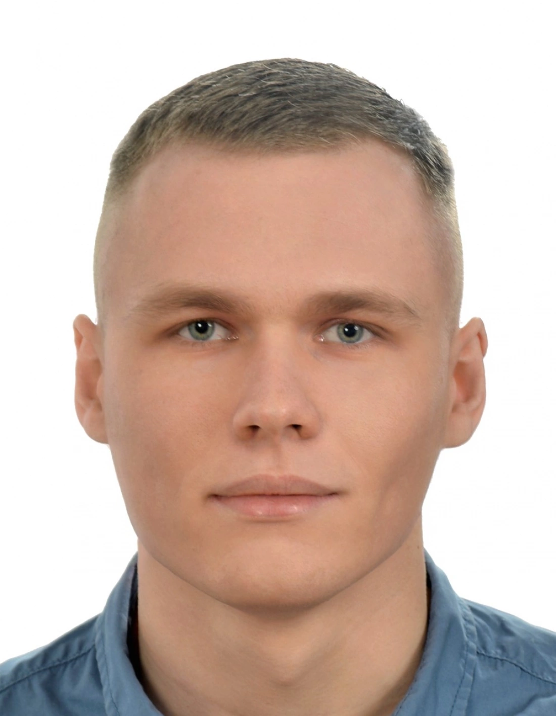 Portret młodego mężczyzny z krótkimi włosami, w niebieskiej koszuli.