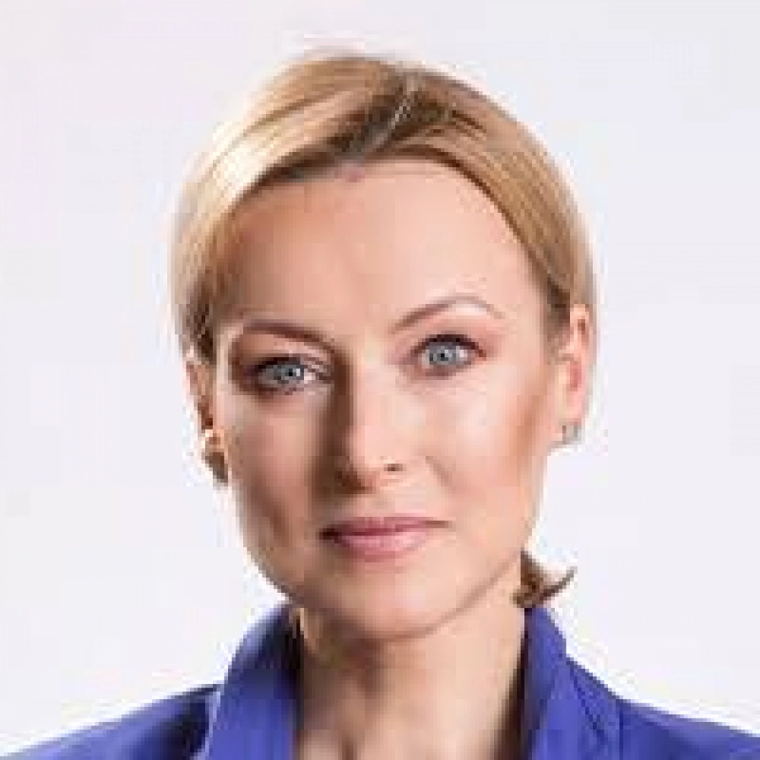 Portret kobiety z blond włosami i niebieskimi oczami, ubraną w niebieską bluzkę.