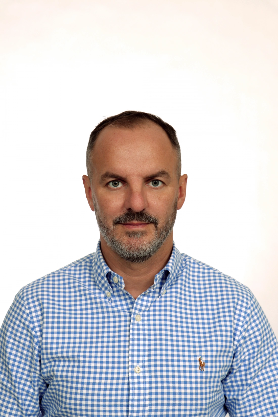 Mężczyzna z brodą, w niebieskiej koszuli w kratę.