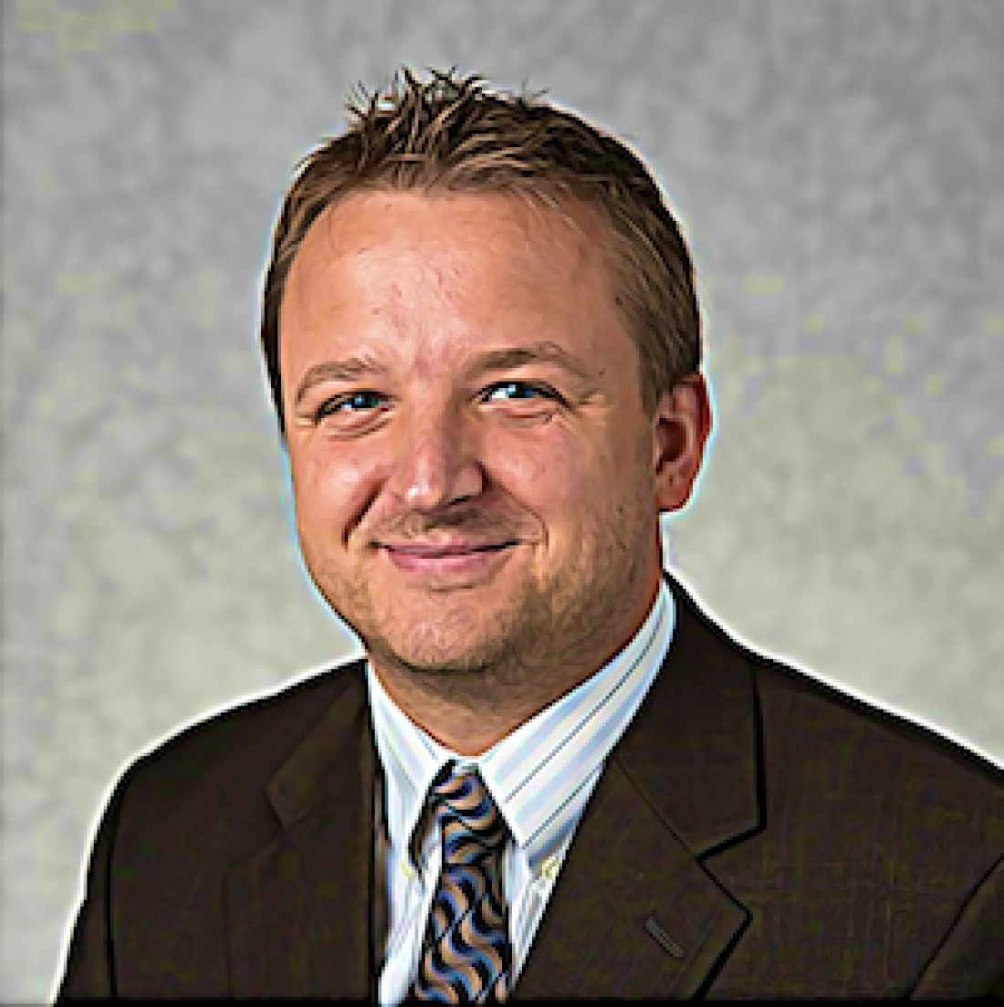 Mężczyzna w garniturze z uśmiechem, na tle jasnego tła.