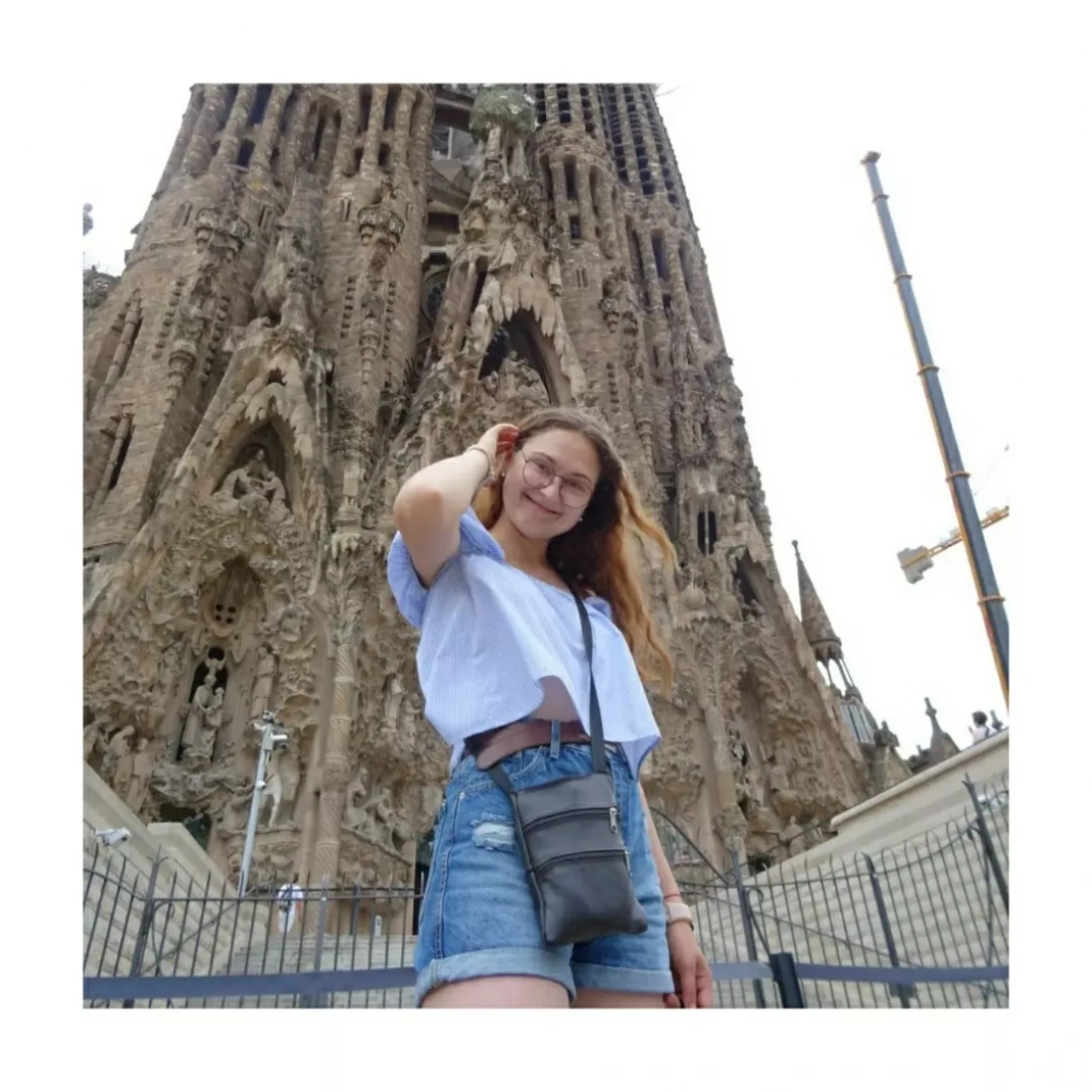 Młoda osoba uśmiecha się przed imponującą, bogato zdobioną architekturą.