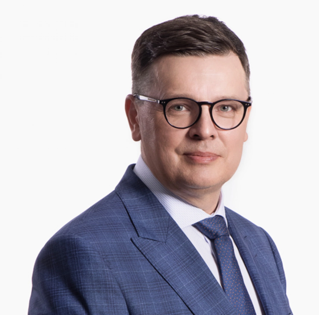 Mężczyzna w okularach, ubrany w niebieski garnitur.